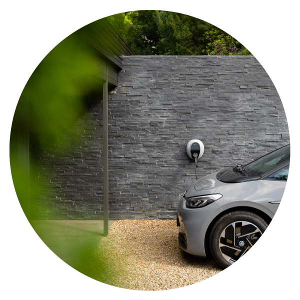 Pod Point domestic Solo 3 installed on a grey slate wall and plugged in to a grey car parked in front