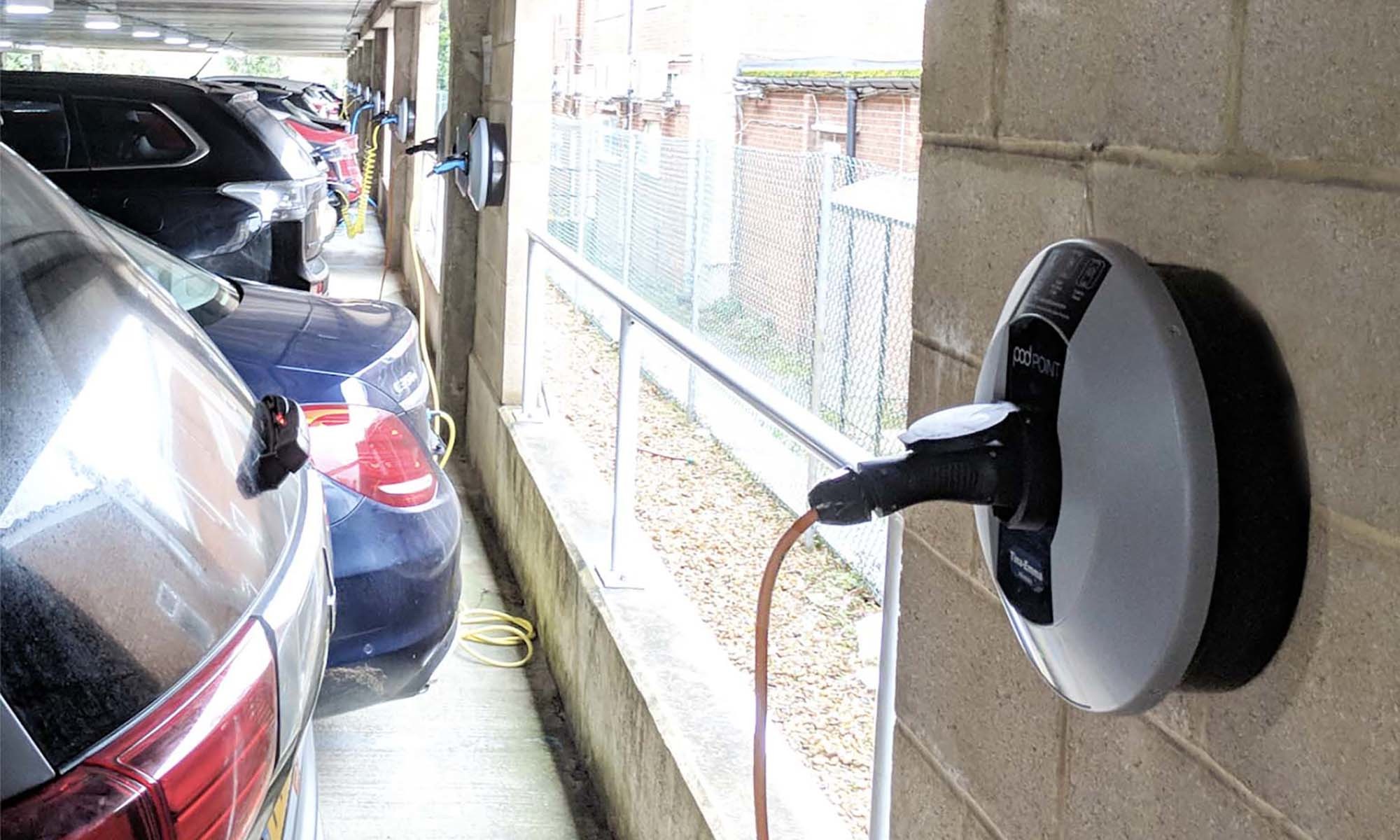 A close up of a Pod Point Solo 3 installed on a white brick wall in Skanska's UK indoor car park