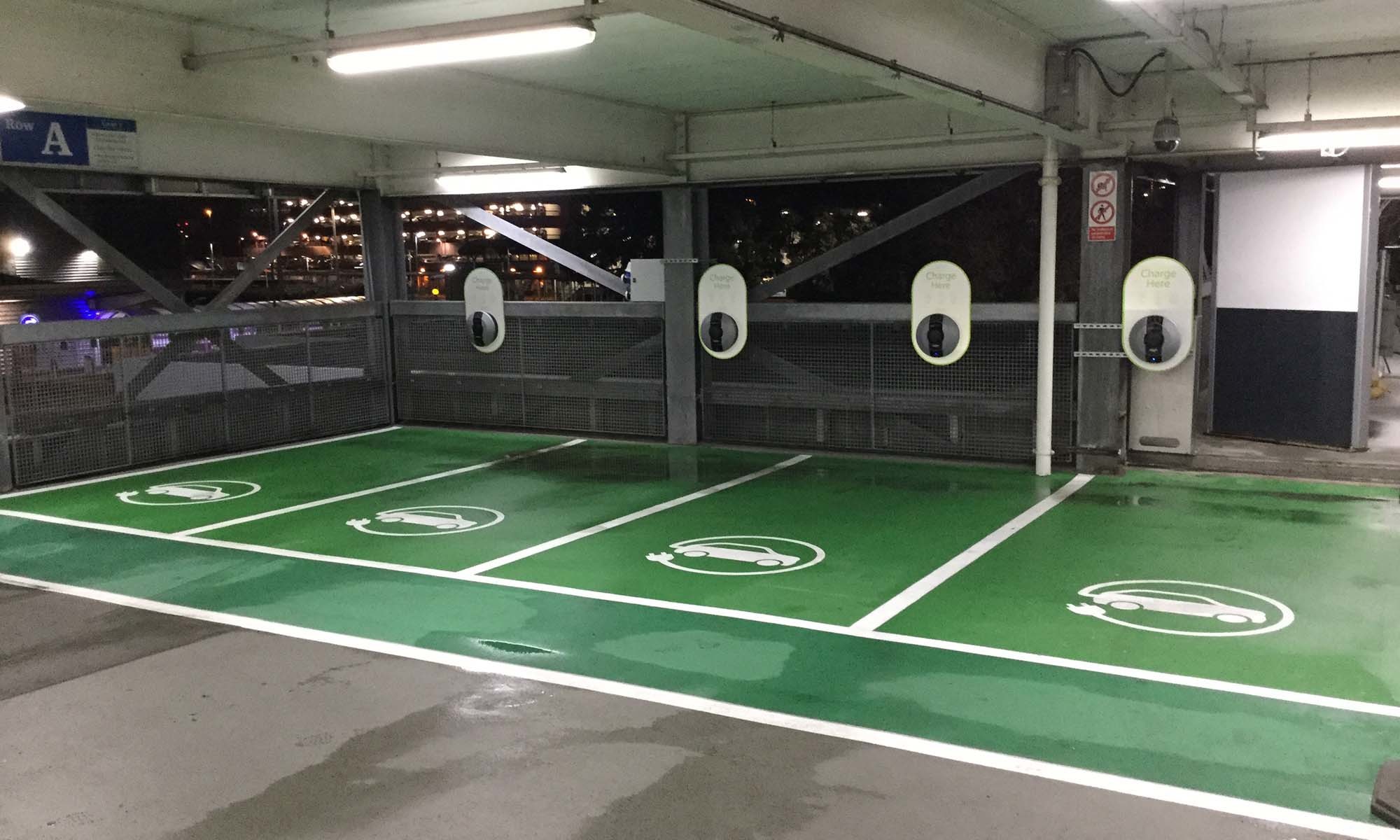 A wide shot of 4 indoor green EV parking bays, with 4 Pod Point Solo 3's installed for each bay.