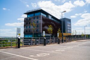 Wide shot of three Pod Point Twin Chargers in-front of the modern glass Exeter Chiefs building