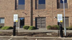 Two Pod Point twin chargers with signage above each, installed in front of Merchant Taylor's school