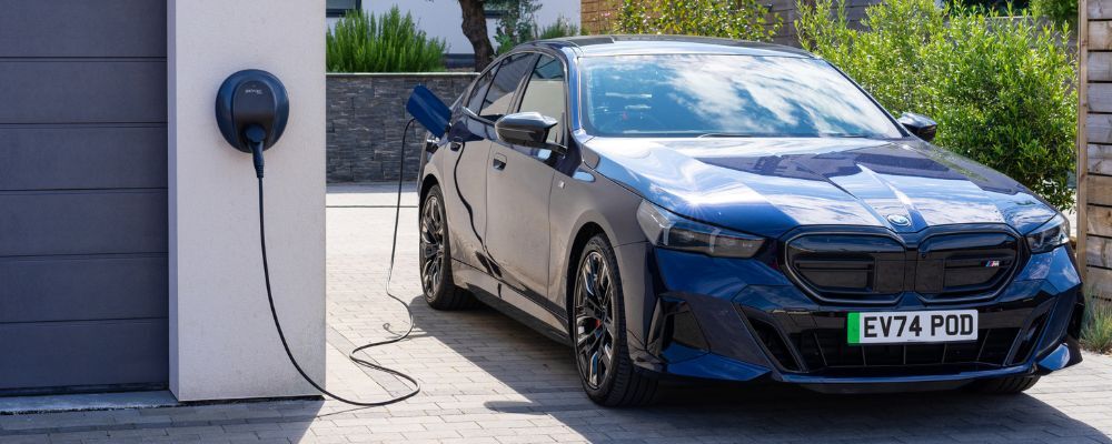 Electric BMW i5 next to a Pod Point Solo 3S home EV charger