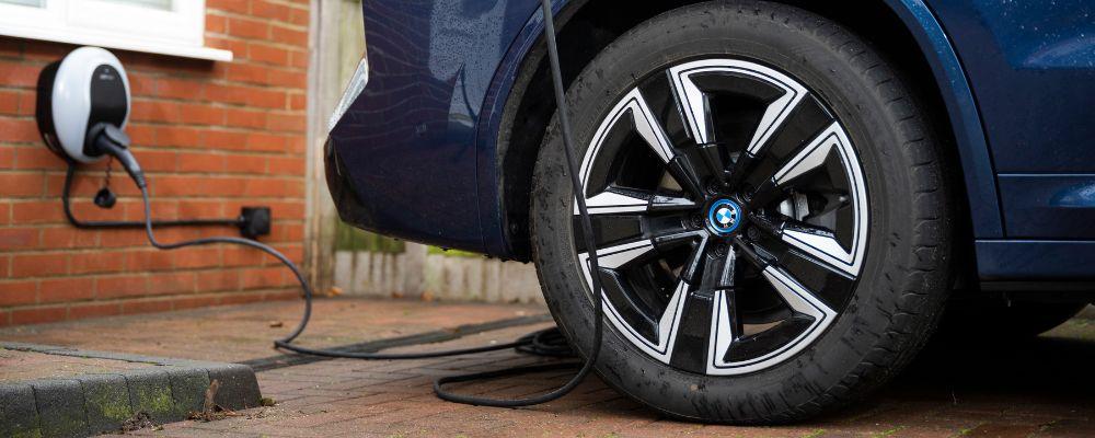 Close up of an electric car wheel with a home charger in the background