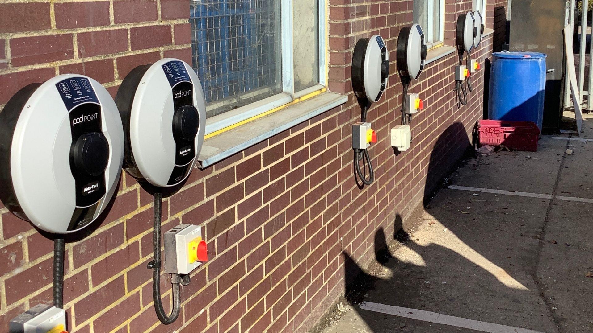 A line of Pod Point Solo 3's installed on the side of a brick building in an outdoor car park